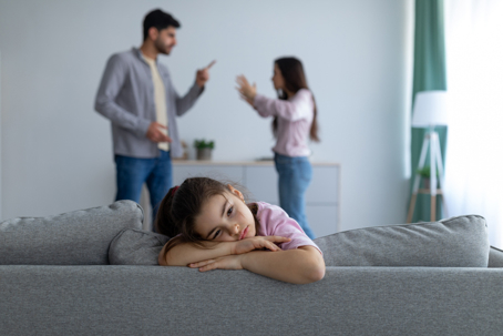 sad child with parents fighting in the background