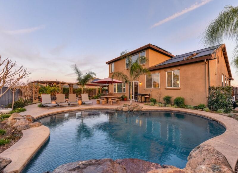 Brown concrete house near a pool.